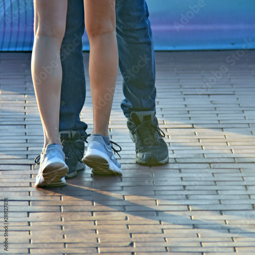 feet of a dancing couple male and female in sneakers, blurred background