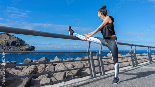 Attractive jogger woman warming the legs before go to running. Athlete runner standing with balance stretch her fit body with vitality to exercise in the seaside