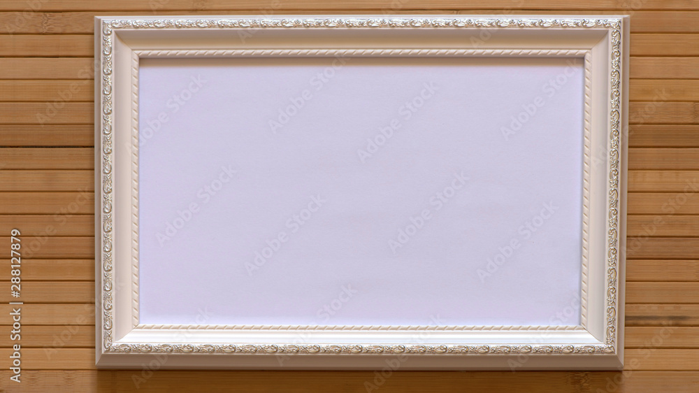 Fototapeta premium White frame with empty white canvas on natural bamboo wall. Horizontal picture 16:9 with useful design for input your inside text, image etc.