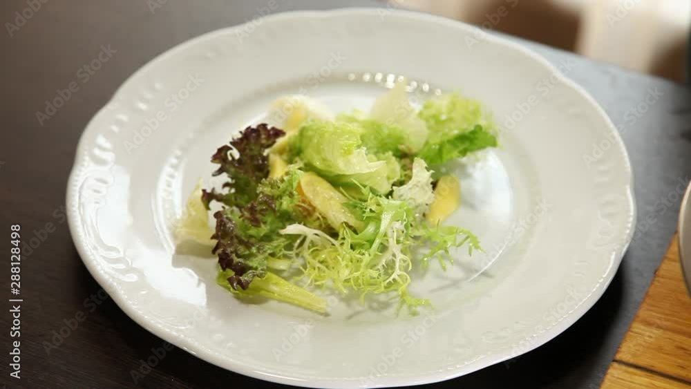 The chef puts salad leaves, slices of orange, mango, avocado mixed with olive oil on a plate The chef puts salad leaves, slices of orange, mango, avocado mixed with olive oil on a plate