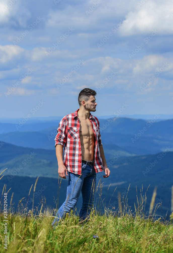 Hiking concept. Power of nature. Man unbuttoned shirt stand top mountain landscape background. Muscular tourist walk mountain hill. Strong hiker muscular torso. Athlete muscular guy relax mountains