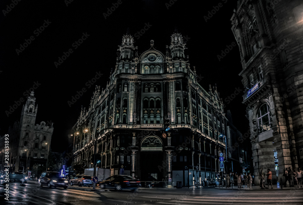 Budapest / Hungary - August 29 2019: Ancient beautiful gothic building and street car traffic on the night streets of Budapest, Hungary. Tourist historical quarter of the capital of Hungary