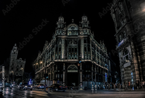 Budapest / Hungary - August 29 2019: Ancient beautiful gothic building and street car traffic on the night streets of Budapest, Hungary. Tourist historical quarter of the capital of Hungary