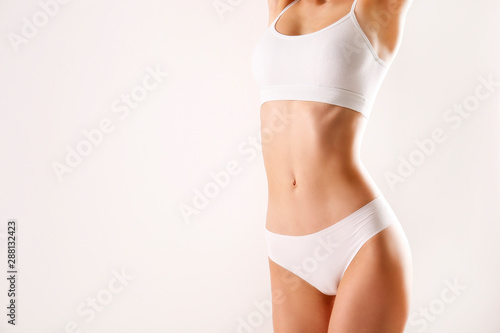 Close up shot of unrecognizable fit woman in lingerie isolated on white background. Torso of slim attractive female with flat belly in white underwear. Copy space for text. photo