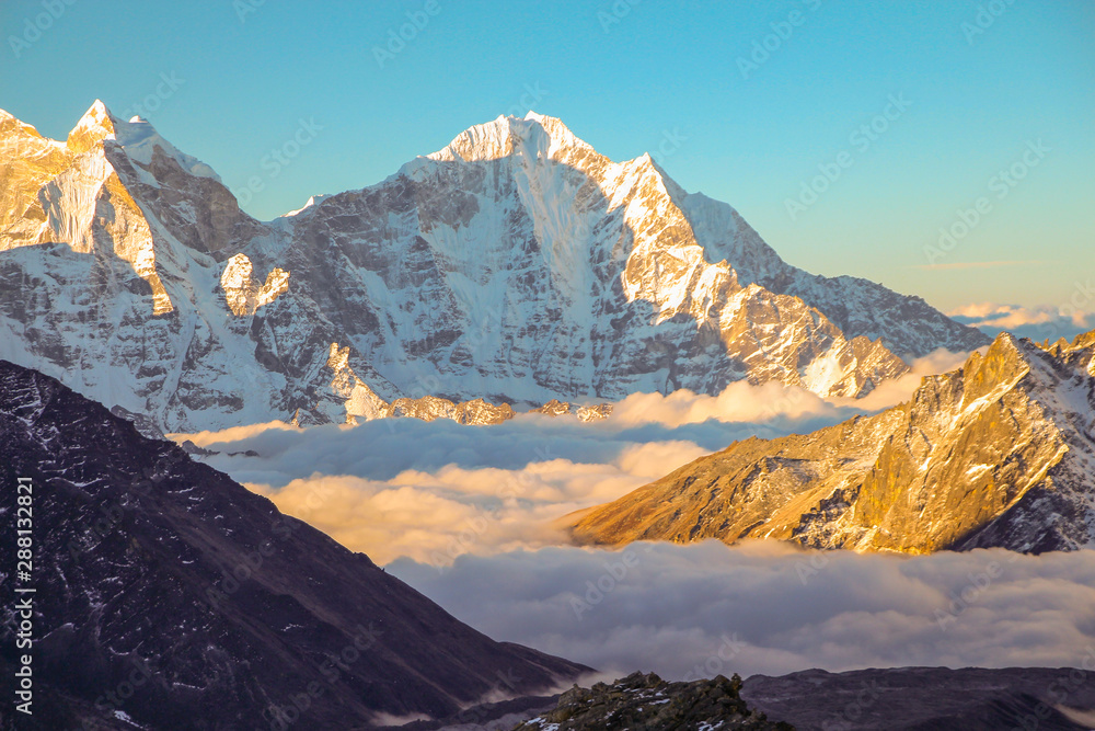 View of Tobuche mountain in the early morning from the summit of Kala Patthar in Nepal. The valley at the base of the mountain is covered with clouds. Nature, mountains, sunset and sunrise concept.