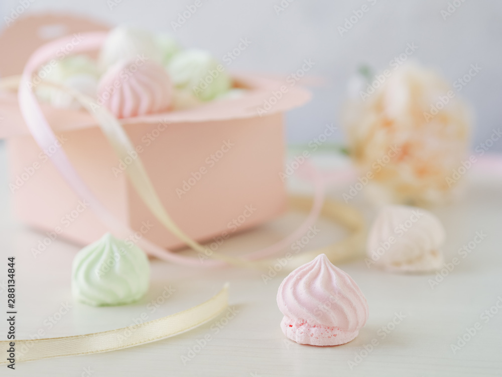 Pastel romantic background with small meringues in a box, flower and ribbons. Pastel romantic background with small meringues in a box, flower and ribbons.
