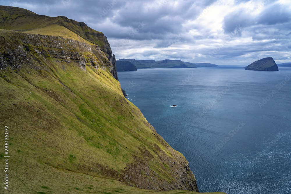 Dramatic landscape of Faroe Islands with grass meadows and rocky cliffs in stormy weather. Dramatic landscape of Faroe Islands with grass meadows and rocky cliffs in stormy weather.
