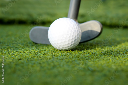 Golfball und Putter auf dem Grün