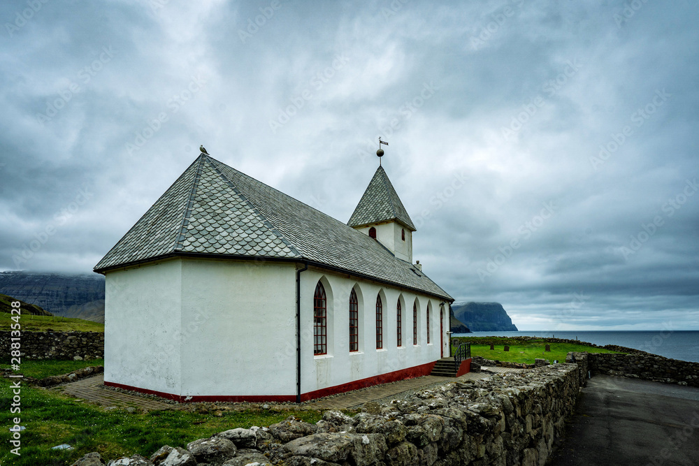 Typical white village's church in Faroe Islands surrounded with dramatic landscape. Typical white village's church in Faroe Islands surrounded with dramatic landscape.