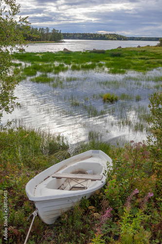 Shabby white boat on the bank of the picturesque Kalix River in Northern Sweden photo