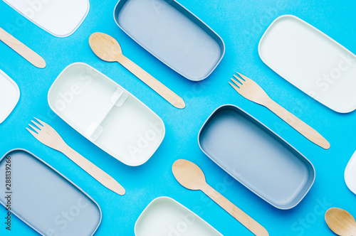 Llunch boxes with wooden forks and spoons on blue background photo