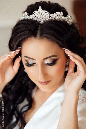 Beautiful bride portrait wedding makeup and hairstyle, girl in diamonds tiara, jewelry model, fashion bride gorgeous beauty. Close up portrait of Beautiful bride lowered her eyes down, shows makeup.