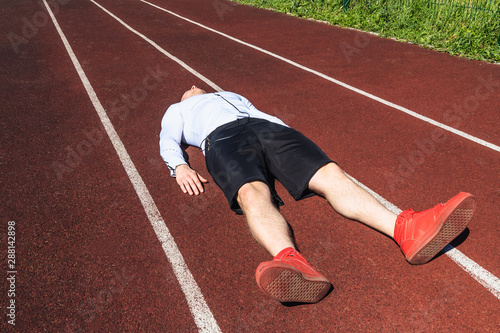 The young athlete is exhausted from training in hot weather. The athlete is on the treadmill sports stadium.