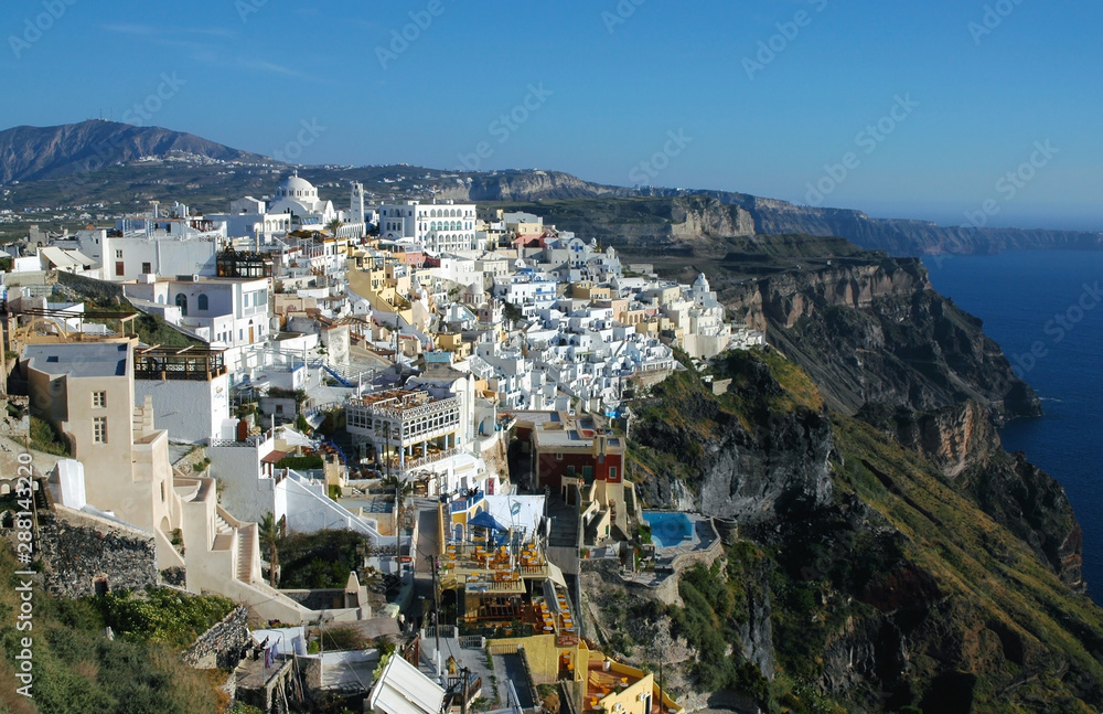 View of Fira on the island of Santorini, Greece. Fira is the main town of Santorini. Santorini has many colorful houses. Pretty Fira, Santorini, Greece with blue sky and blue, white and yellow houses.