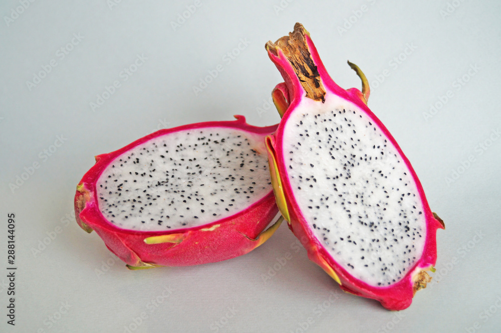 Dragon fruit or pitaya with pink peel and juicy white pulp with black seeds on a light background