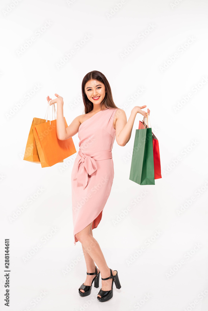 Portrait of a happy smile young asia girl dressed in pink dress holding shopping bags and looking away white background Portrait of a happy smile young asia girl dressed in pink dress holding shopping bags and looking away white background