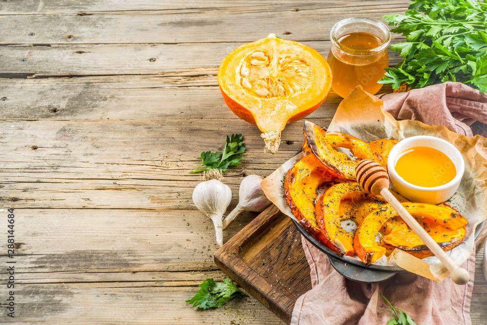 Autumn vegetarian food recipe. Organic roasted vegetables, Baked fried Hokkaido pumpkin with olive oil, herbs, garlic and honey. On wooden rustic background, copy space - obrazy, fototapety, plakaty 