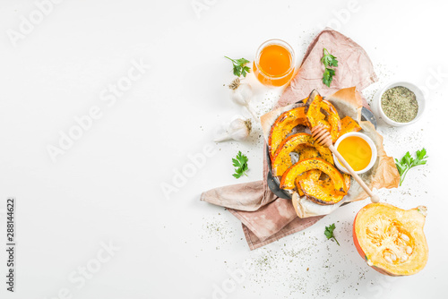 Autumn vegetarian food recipe. Organic roasted vegetables, Baked fried Hokkaido pumpkin with olive oil, herbs, garlic and honey. On a white stone background, copy space