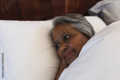 Senior woman lying in bed at home photo