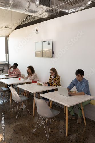 Business colleagues using multimedia devices in canteen