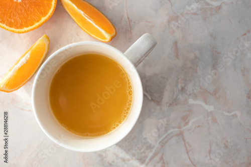 Close-up of cup of fresh homemade orange juice and cut oranges on table