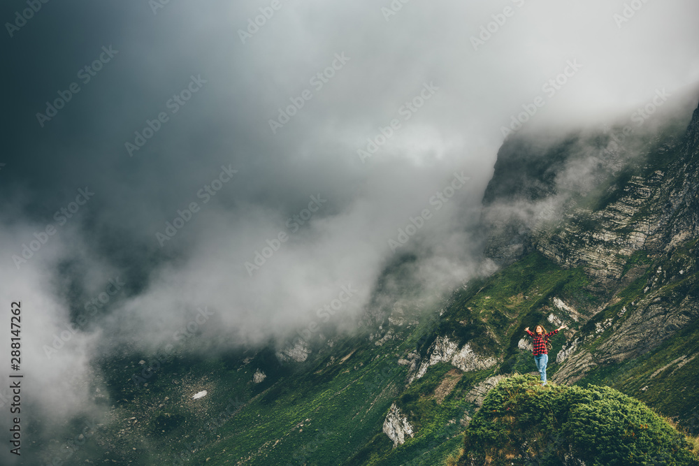 Young woman hiker enjoy the view on mountain peak. Happy traveler hipster standing on top of sunny mountains. Atmospheric moment. Travel, freedom and happiness.
