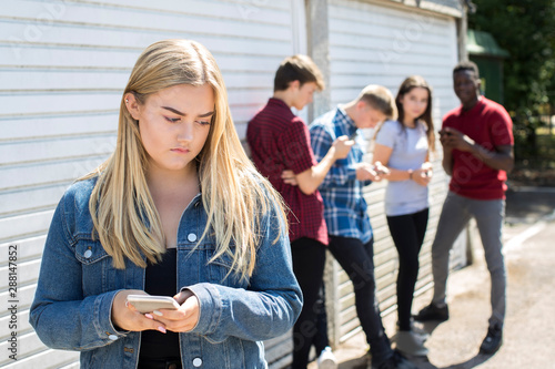 Obraz na plátně Unhappy Teenage Girl Being Bullied By Text Message Outdoors
