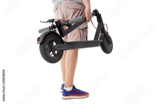 The guy holds a folded electric scooter on a white background