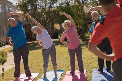 Trainer training senior people in performing exercise