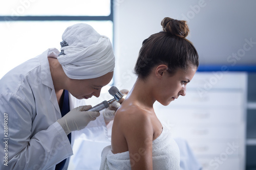 Female doctor checking patient with dermatoscopy photo