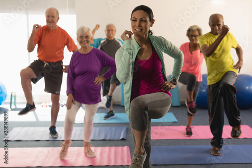 Cuadro en lienzo Front view of female trainer assisting senior people in fitness studio
