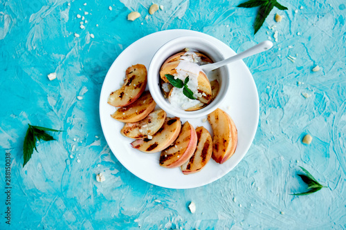 Grilled peach with ice creame on white plate on blue background. Grilled dessert. Barbecue fruit. Copy space. Healthy food. Vegan food. photo