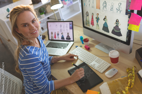 Female fashion designer looking at camera while working at desk 
