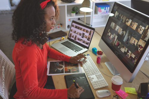 Female graphic designer using graphic tablet at desk 