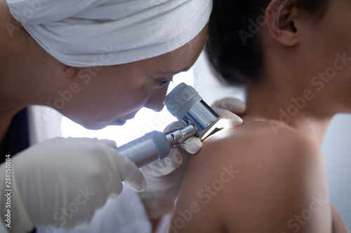 Female doctor checking woman body with dermatoscopy photo