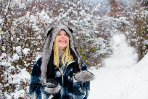 Happy girl playing snow winter day. Winter holidays. Beautiful woman in warm coat, fur hat and mittens. Cold winter weather. Christmas girl in warm clothing in winter park. Fashion girl in wintertime. © Svitlana