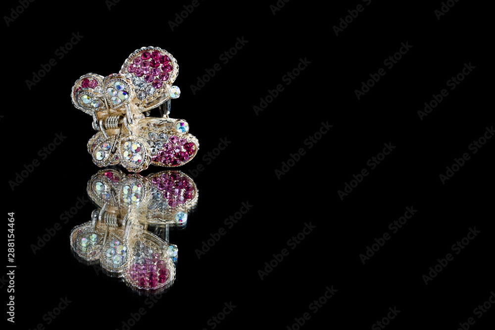 Butterfly barrette with precious stones on a mirror on a black background isolate Butterfly barrette with precious stones on a mirror on a black background isolate
