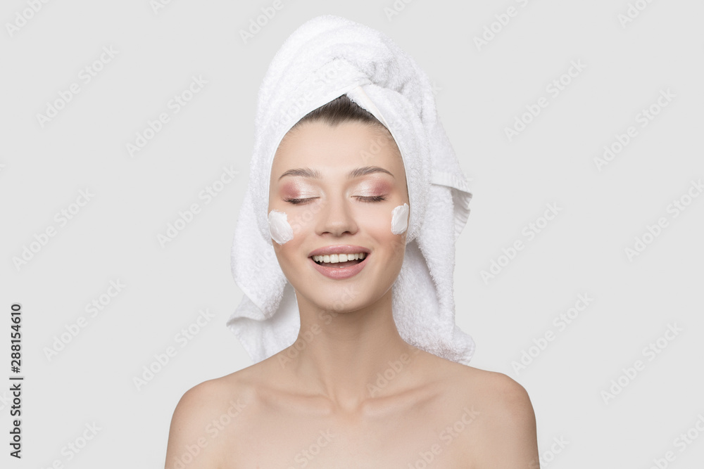 woman is laughing with cream on her face and a towel on her head. White background. Skin care concept woman is laughing with cream on her face and a towel on her head. White background. Skin care concept