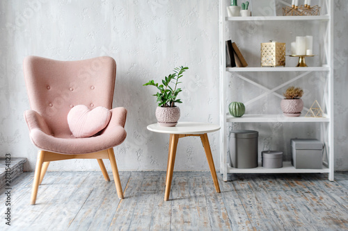 Stylish pink armchair with heart shaped pillow in a bright minimalist interior photo