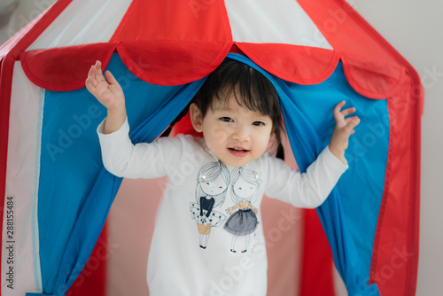 Asian Cute toddler girl standing in white dress in tent lodge and smile in living room at home..