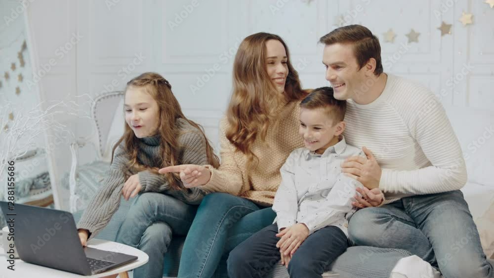 Smiling family watching funny video at notebook together Smiling family watching funny video at notebook together