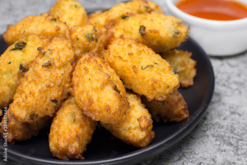 Fried rice balls called bolinho de arroz in a black plate in rustic background close Fried rice balls called bolinho de arroz in a black plate in rustic background close