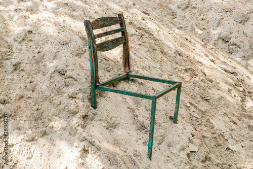 Old broken chair in a pile of sand