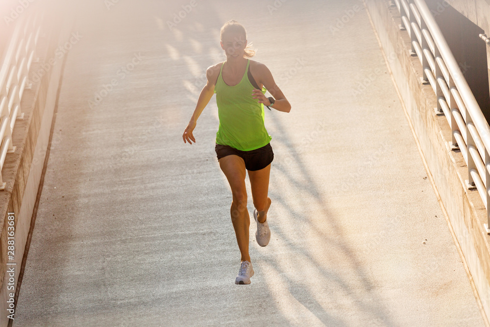 Young woman running on parking level in the city at sunset Young woman running on parking level in the city at sunset