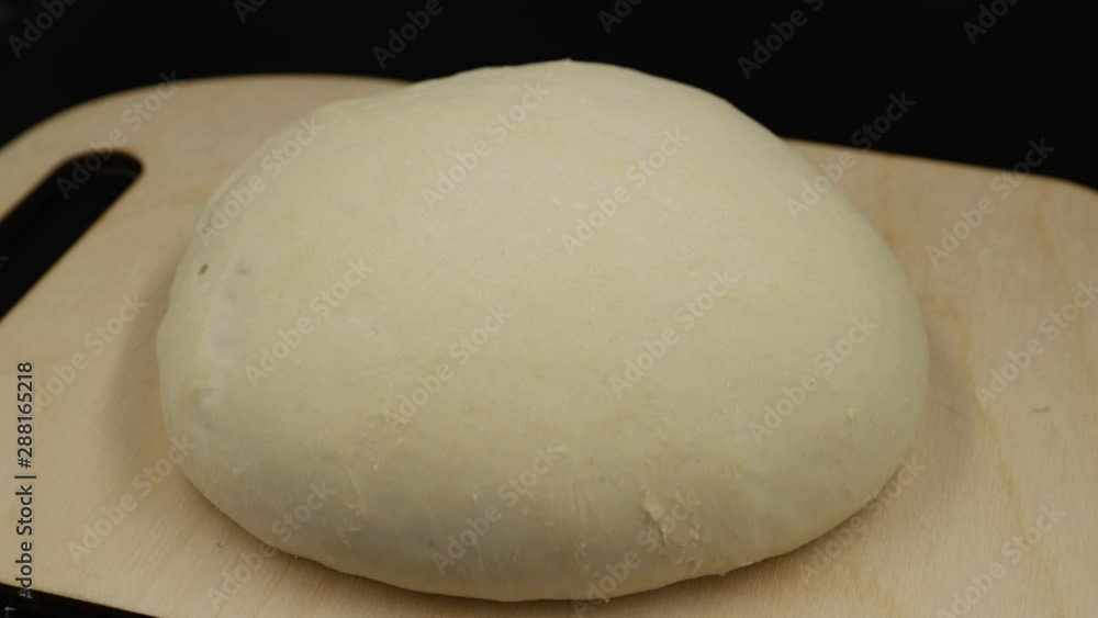 Time lapse. Yeast dough increases in size. The dough on the cutting board rises on black background. Time lapse. Yeast dough increases in size. The dough on the cutting board rises on black background.