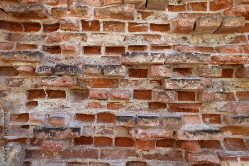 Very old and worn brick wall with red bricks