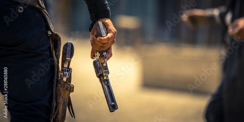 Man holding his six-shooter ready for a gunfight, Western movie set photo