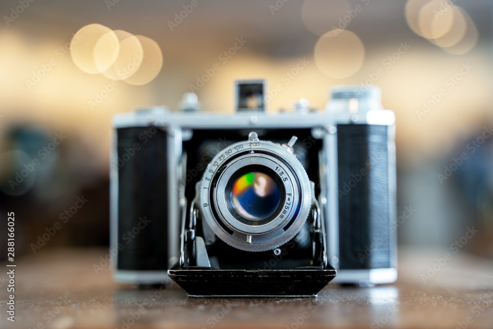 Retro film photo camera isolated on blurred background at light bokeh..