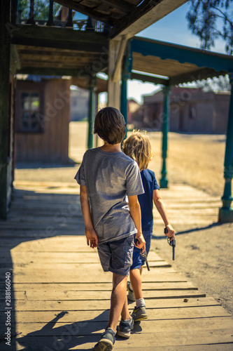 Two boys holding gun replica, walking in a western old town © Nicolas Viard