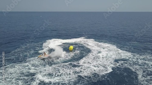 Aerial drone shot of a man driving and swirling jet ski in azure water. Rhodes island, Greece photo